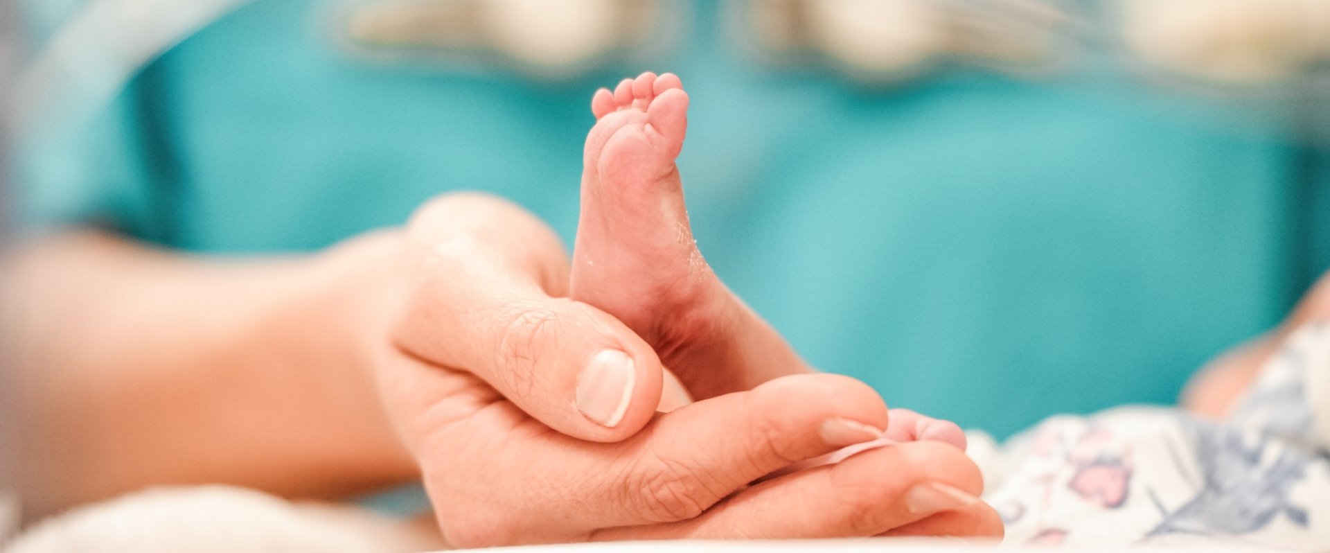 Pflegerin hält die Füße eines Neugeborenen Kindes