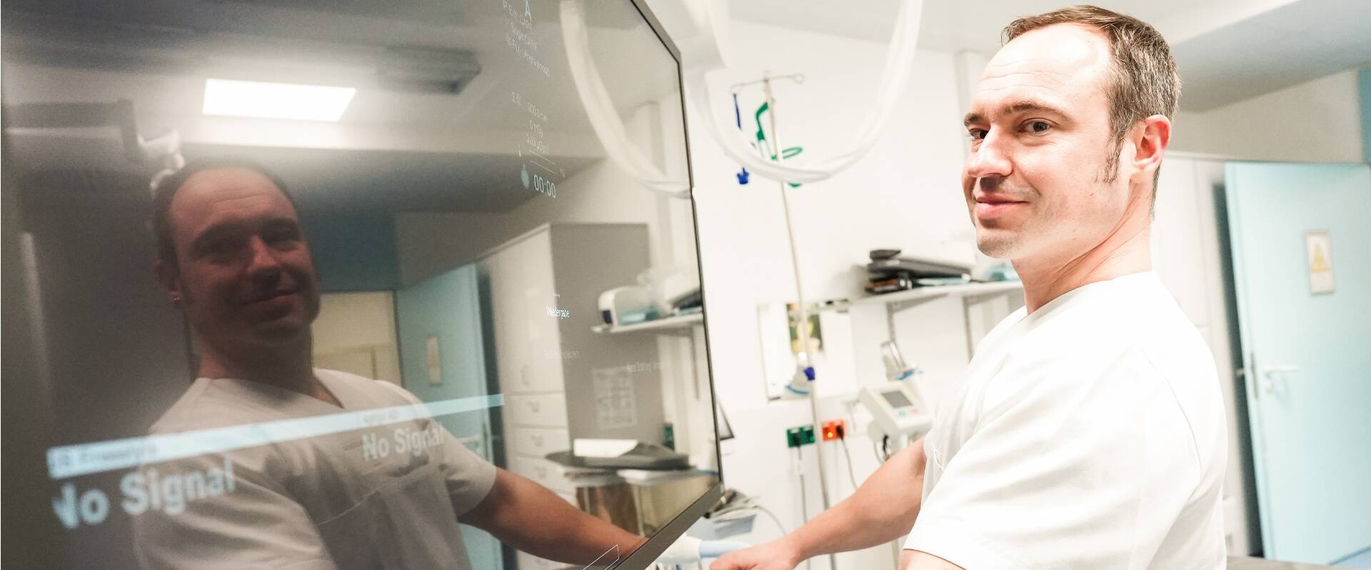 Ein Mann, rechts im Bild, wird von einem großen Bildschirm links, gespiegelt.