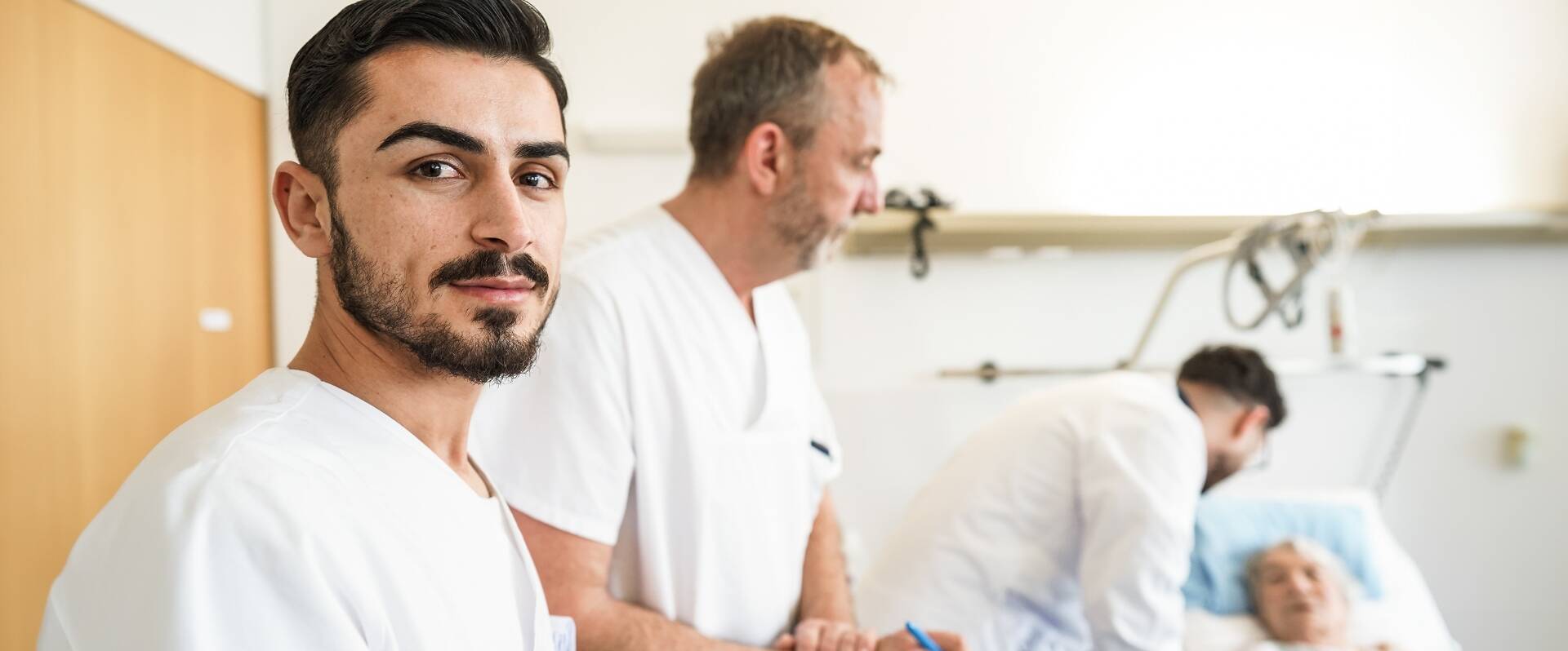 Drei Ärzte stellen eine Diagnose im Patientenzimmer