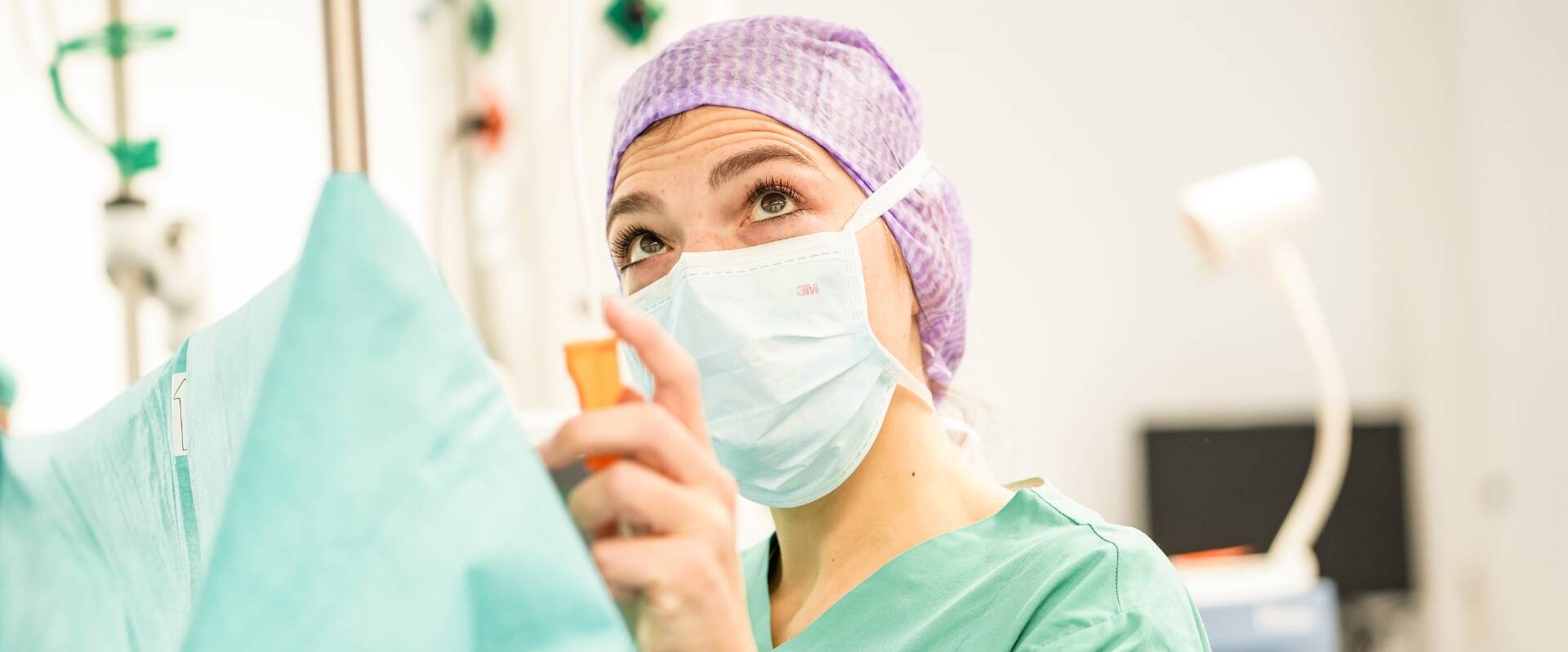 Ärztin mit Maske und Haarnetz im OP Saal