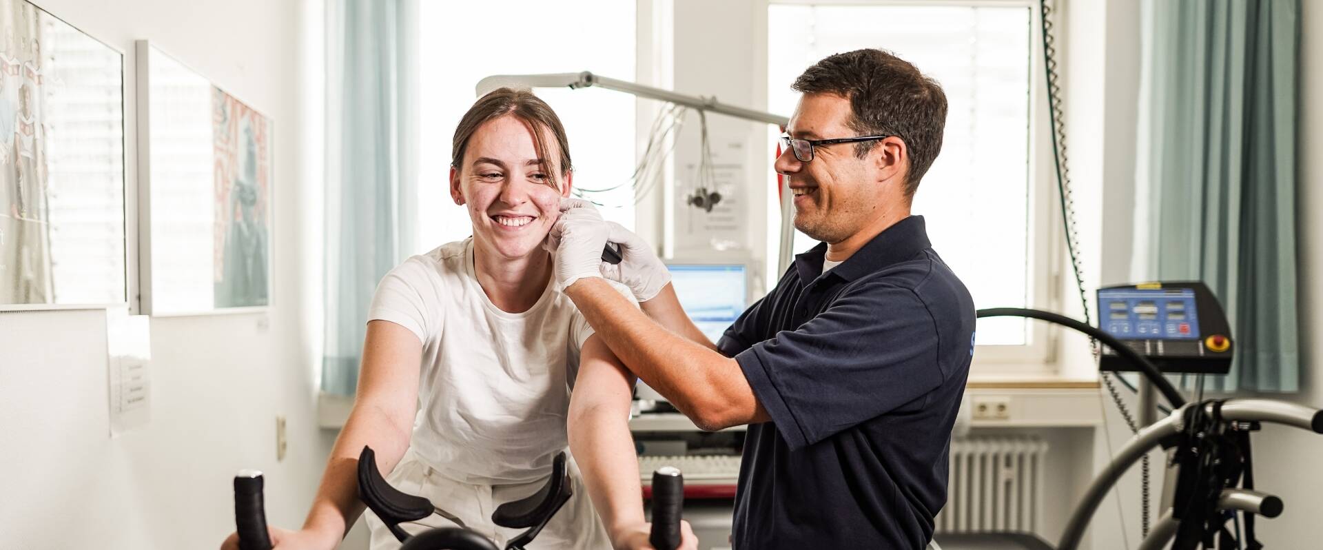 Männlicher Trainer gibt trainierender Frau auf dem Ergometer Anweisungen