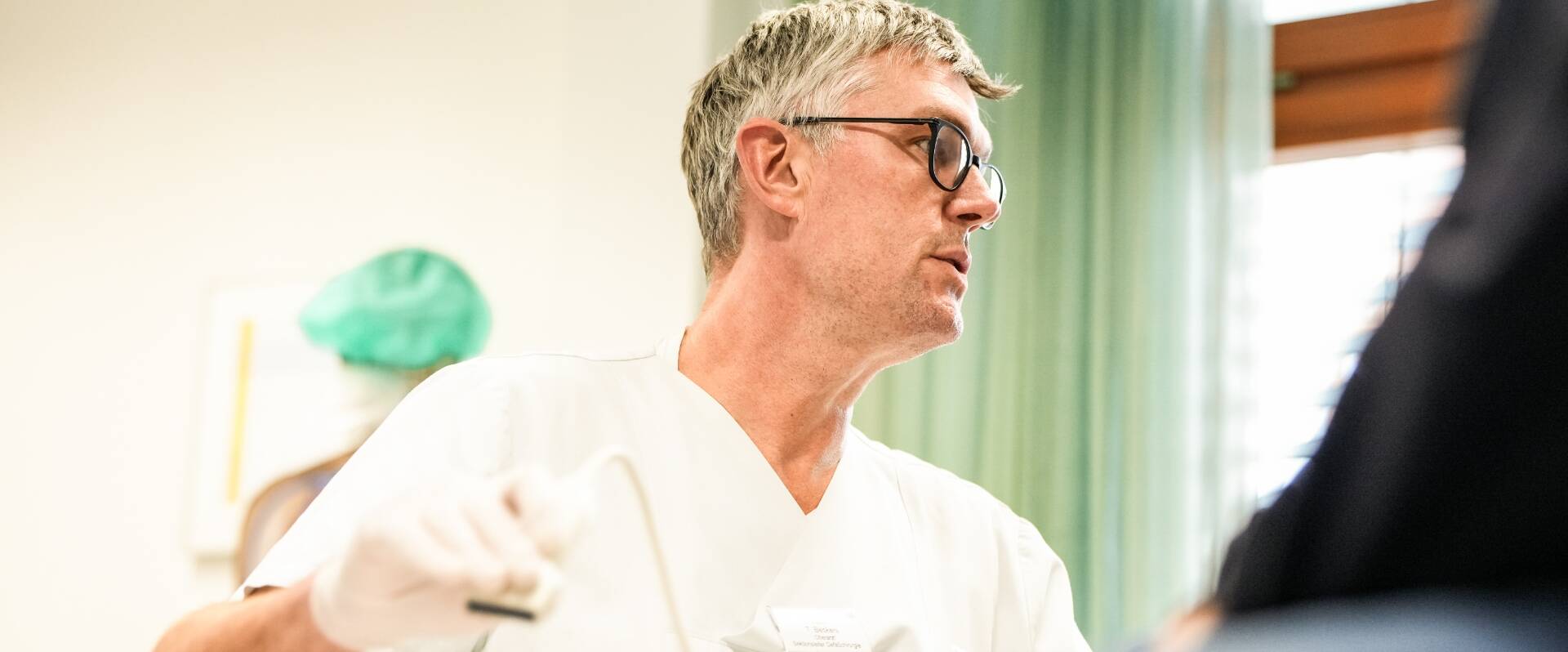 Ein Arzt überblickt die Arbeit eines Mitarbeiters von der Seite